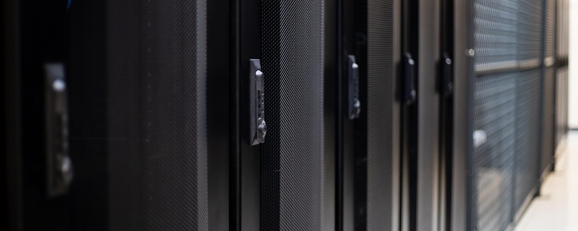 Row of black server rack doors with locking handles in a tym2 data hall